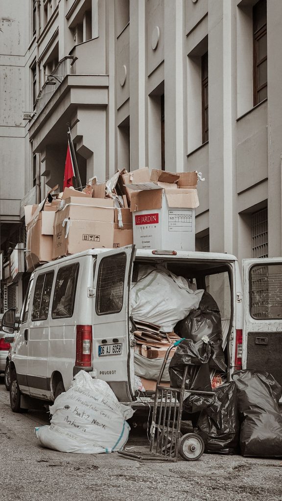 Van loaded with boxes and bags parked in a narrow alleyway behind terraced housing