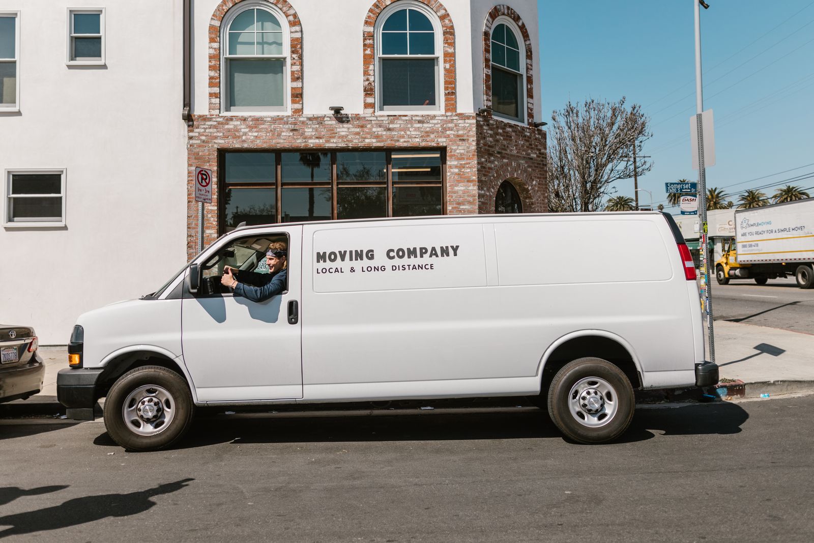 White box-bodied removal van parked on a city street on a sunny day